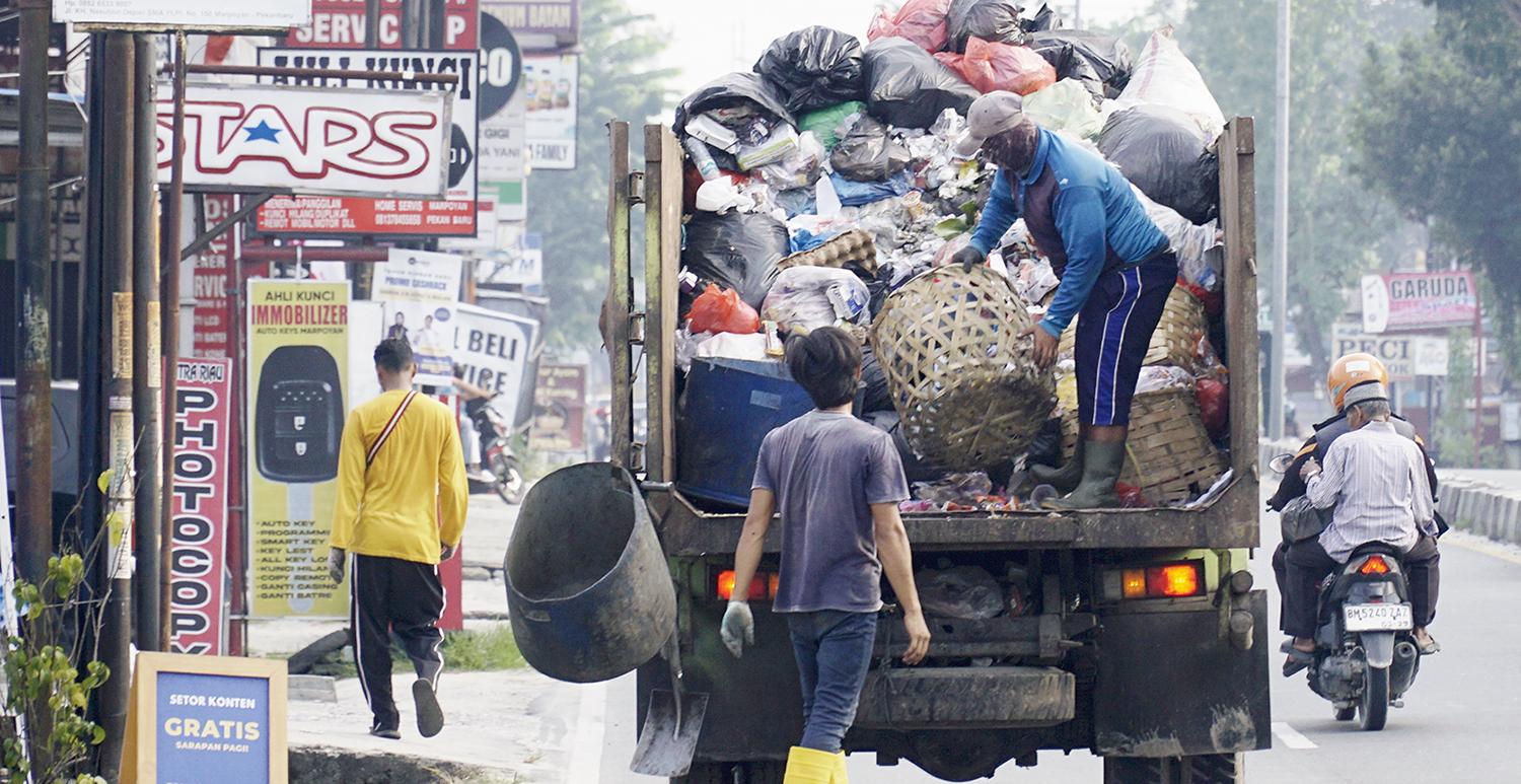 Pekerja angkut sampah kedalam truk ketika melintas di Jalan Kaharuddin Nasution, Pekanbaru, Ahad (5/10/2025) ft: MHD AKHWAN/RIAUPOS