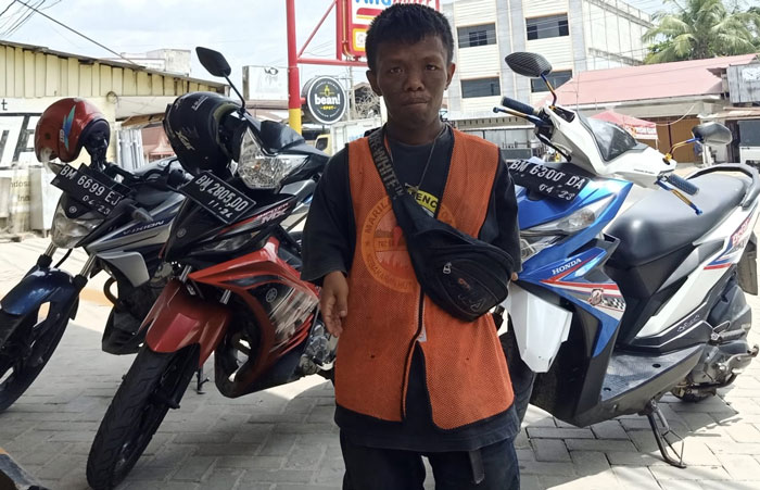 Petugas parkir di Kecamatan Mandau saat mengatur kendaraan yang masuk ke dalam sebuah ruko pedagang.