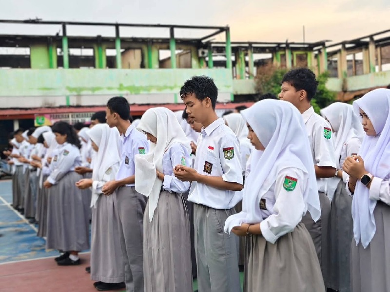 Siswa SMAN 1 Tebingtinggi ketika menyambut kehadiran perwakilan pemerintah provinsi di halaman sekolah yang dikelilingi riang kelas bekas terbakar, Senin (6/10/2025).