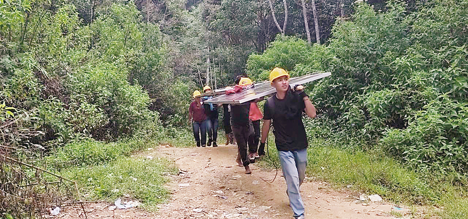 bahu membahu: Dengan penuh semangat gotong royong, petugas PLN dan warga bahu membahu memikul panel surya seberat hampir 100 kilogram menuju lokasi pemasangan di sekolah-sekolah.