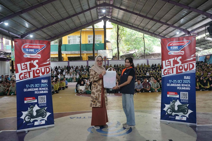 Staff Event DBL Shabina Aasha menyerahkan cendera mata kepada Kepala Sekolah SMAN 1 Pekanbaru Baini MPd saat roadshow Honda DBL with Kopi Good Day 2025 Riau di  SMA N 1 Pekanbaru, Kamis (9/10/2025).