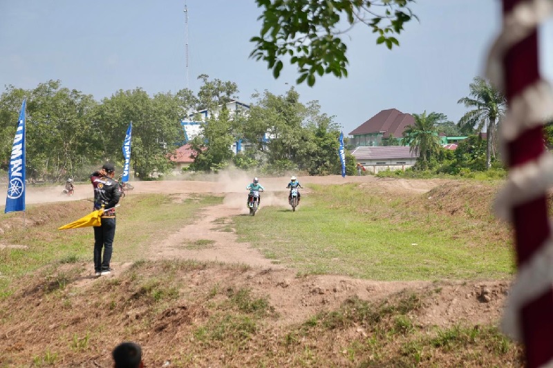 Dua rider bersaing ketat di lintasan Sirkuit Wonosari dalam Kejuaraan Motocross dan Grasstrack yang ditandai dengan pengibasan bendera start di Sirkuit Desa Wonosari, Kecamatan Bengkalis.