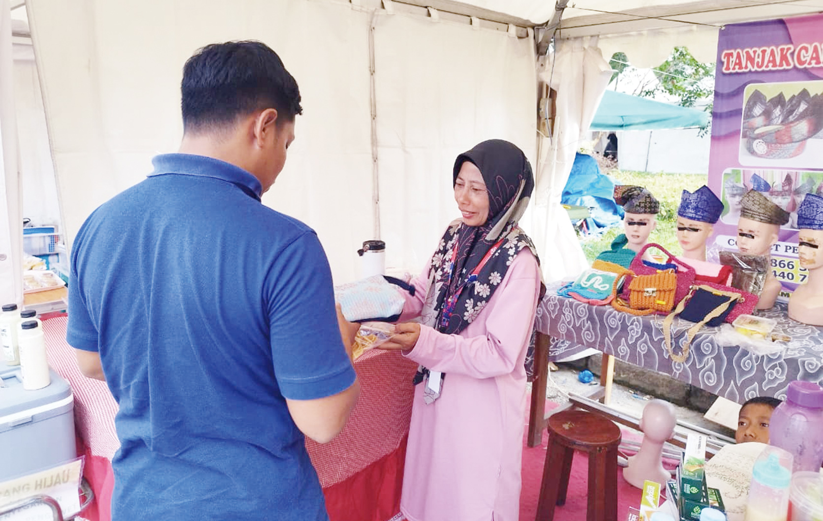 Perajin rajutan asal Pelalawan yang menjadi mitra bina Community Development RAPP Yessi Heriyani melayani pengunjung saat Helat Pelalawan 2025 yang digelar di Taman Kreatif Pangkalankerinci, baru-baru ini.