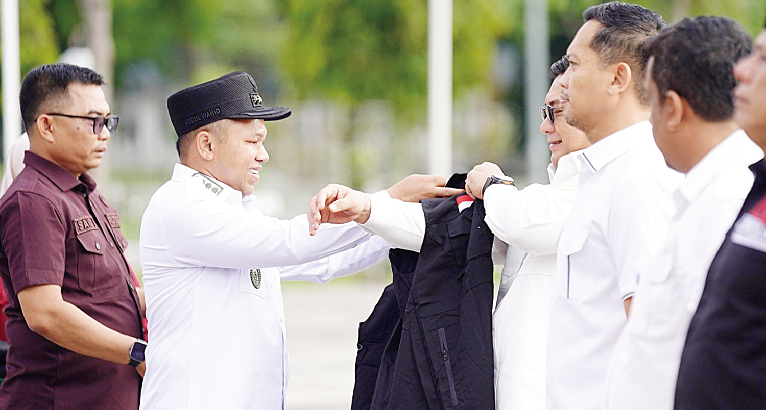 PASANGKAN ROMPI: Gubri Abdul Wahid memasangkan rompi kepada Satgas PHK Riau di halaman Kantor Gubernur Riau, Rabu (15/10/2025).