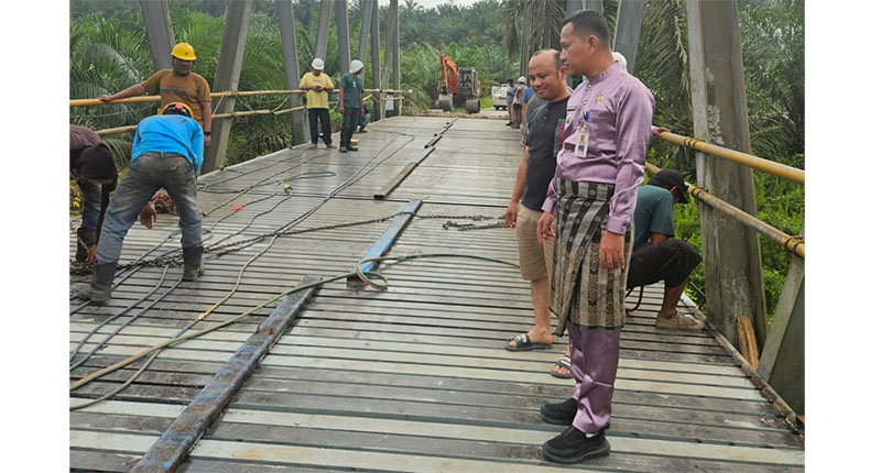 Camat Singingi, Saparman meninjau pekerjaan pemasangan lantai jembatan penghubung Desa Sungai Bawang-Air Mas, pekan kemarin.