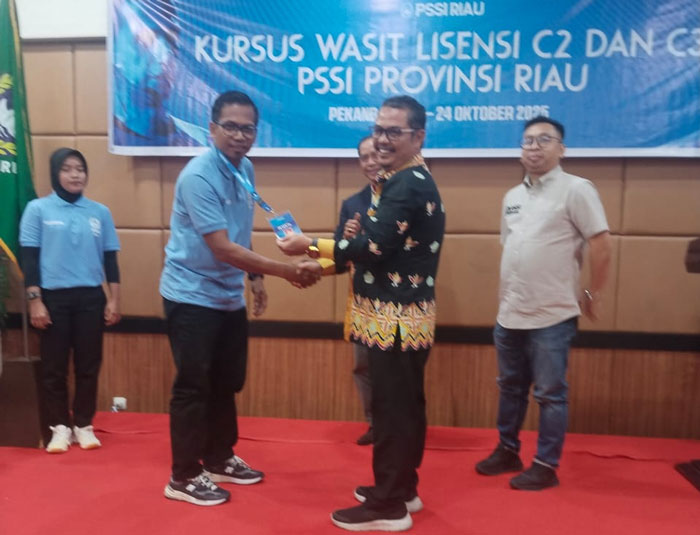 Kepala Bidang Peningkatan Prestasi Olahraga Dispora Riau Amir Azan mengalungkan ID card kepada seorang peserta saat pembukaan kursus wasit C2 dan C3 yang digelar Asprov PSSI Riau di Hotel Angkasa