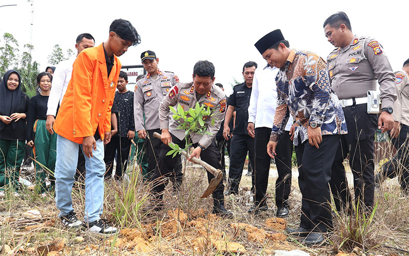 Kapolres AKBP John Louis Letedara SIK melakukan penamaman pohon usai memberikan edukasi program Green Policing di kampus PNP Pelalawan, Selasa (21/10/2025).