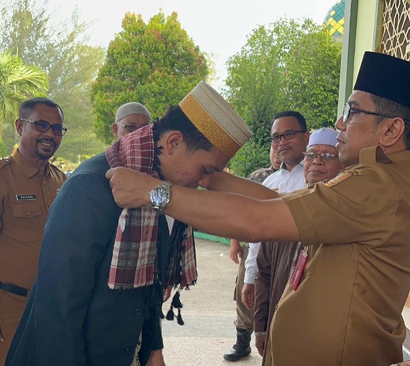 Sekda Kuansing Zulkarnain ST MSi memasangkan selempang pada Aljuanda Kurniansyah peraih Juara I Tahfiz 5 Juz di STQ Nasional saat tiba di Kuansing, Senin (20/10/2025) sore.