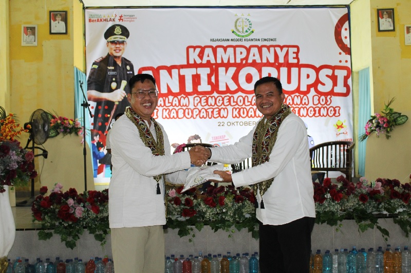 Kajari Kuansing Sahroni SH MH menyerahkan baju kaos antikorupsi kepada Kadis Dikpora Kuansing, H Herizon SPd MM saat kampanye anti korupsi di SMPN 6 Teluk Kuantan, Rabu (22/10/2025).