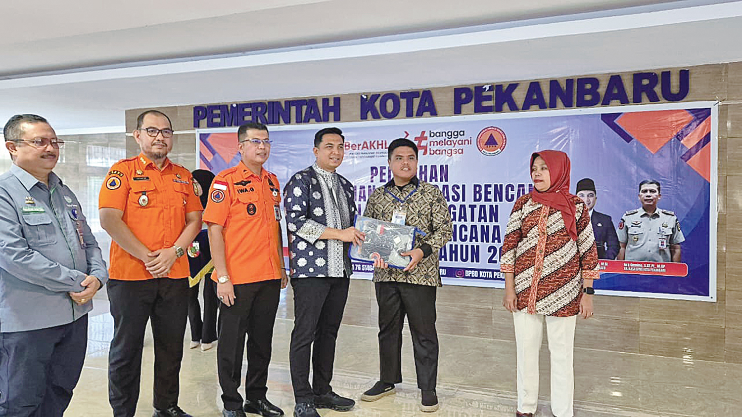 TANDA PESERTA: Pj Sekko Pekanbaru Zulhelmi Arifin (tiga kanan) menyerahkan tanda peserta kepada perwakilan peserta pelatihan pencegahan dan mitigasi bencana di Kantor Mal Pelayanan Publik (MPP) Pekanbaru, Kamis (23/10/2025).