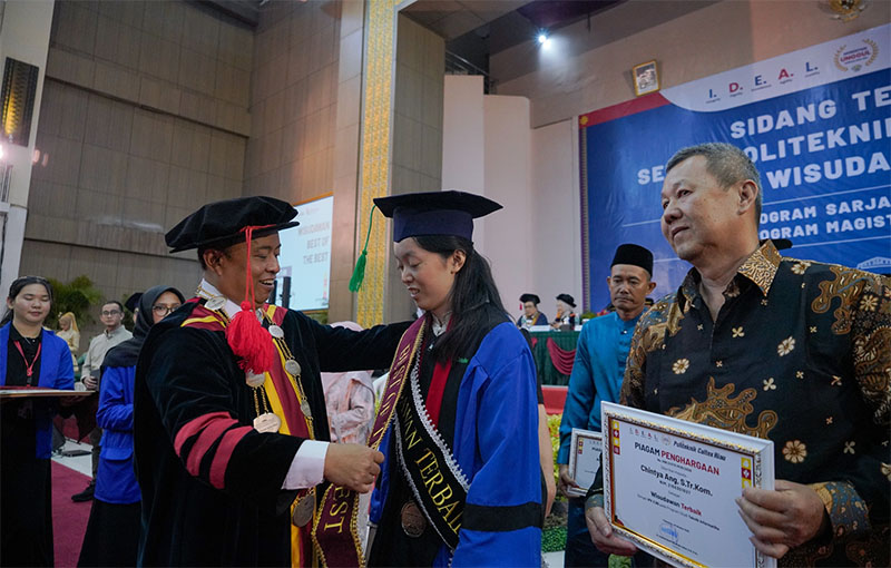 Direktur PCR Dr Dadang Syarif SS memakaikan selempang best of the best Wisudawan terbaik Politeknik Caltex Riau tahun 2025 kepada Chintya Ang, Sabtu (25/10/2025).