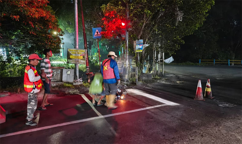 Para pekerja melakukan pengecatan ulang marka jalan di persimpangan Lampu Merah, Jalan Parit Indah - Kelapa Sawit, Rabu (29/10/2025) malam.