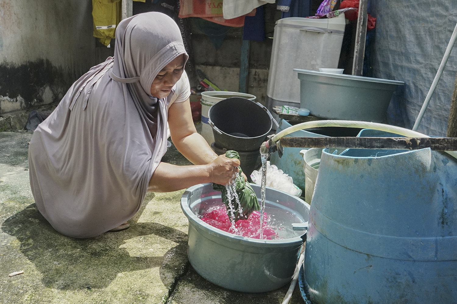 Seorang Warga Sunarti mencuci pakaian menggunakan air yang berasal dari sumur bor air bersih bantuan Pertamina Hulu Rokan, Senin (6/10/2025). Selama lebih dari 40 tahun warga mengalami kesulitan dalam mengakses air bersih.