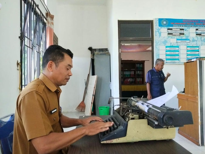 Kasi Pemerintahan Kelurahan Sungai Mempura Afri Candra, menggunakan mesin tik saat memberikan pelayanan, Senin (3/11/2025).