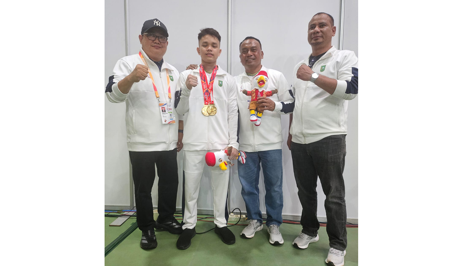 Lifter Riau Kevin Andrian Ramadhan foto bersama Kadispora Riau Yurnalis (dua kanan), CdM Kontingen Riau Rinov Eka Mondrie (kiri), dan Sub Koordinator Pengembangan dan Kemitraan Sarana Prasarana Dispora Riau Beny Saputra (kanan) usai menerima medali emas