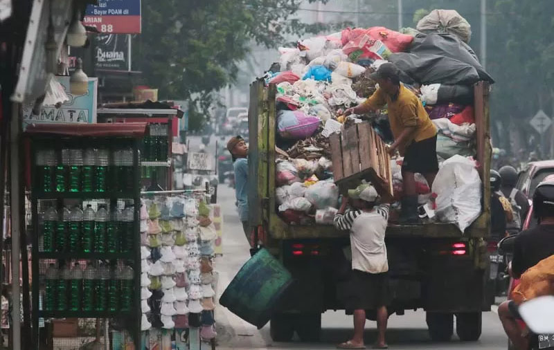 Para pekerja mengangkut sampah ke dalam truk di kawasan Jalan Kaharuddin Nasution, Pekanbaru.