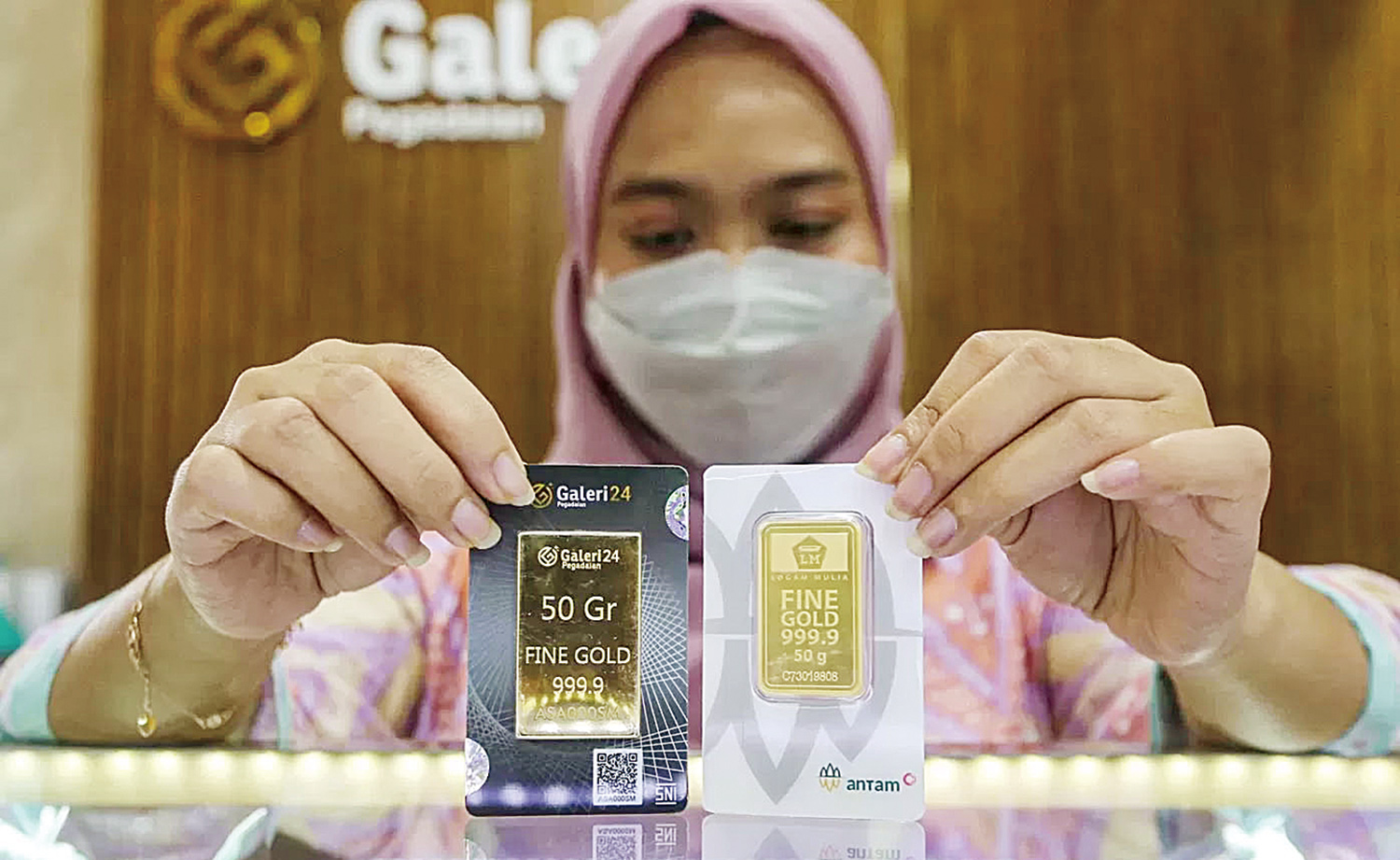Petugas menunjukkan emas Antam di Galeri Pegadaian, belum lama ini. Pada perdagangan, Kamis (6/11/2025) harga emas Antam naik Rp27.000 per gram.