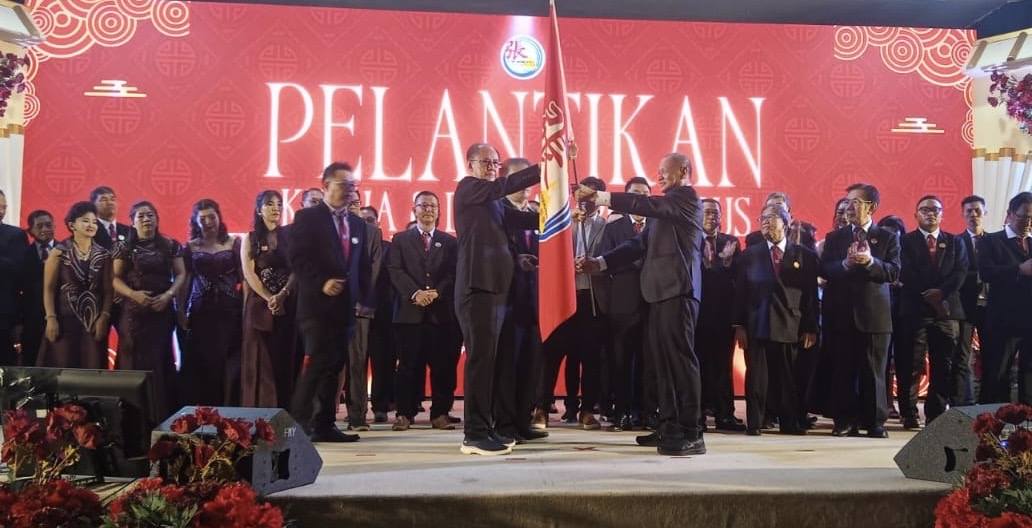 Dewan Pengawas Marga Zhang Riau, Pilemon Piterus (kiri), Ketua Marga Zhang Riau Tio Po Kui (kanan) memegang bendera Persaudaraan Marga Zhang saat pelantikan di Pekanbaru, Sabtu (8/11/2025).