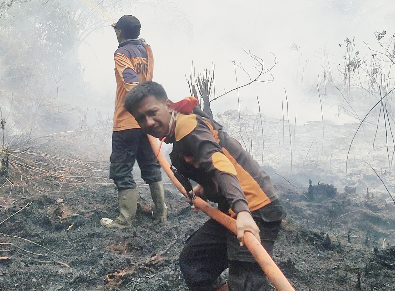 Personel dari tim gabungan Badan Penanggulangan Bencana Daerah Riau menarik selang air saat melakukan pemadaman api yang membakar lahan di Kabupaten Indragiri Hilir, Ahad (9/11/2025).