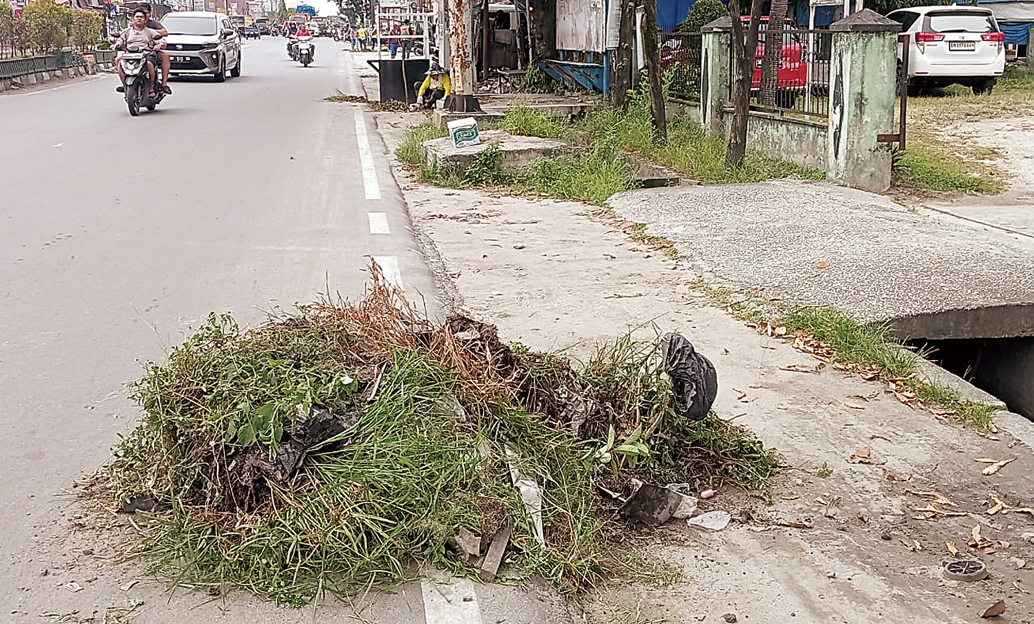 Pasukan kuning PUPR Kota Pekanbaru membersihkan rumput liar dan saluran air yang ada di Jalan Kaharuddin Nasution, Kecamatan Marpoyan Damai, Selasa (11/11/2025).