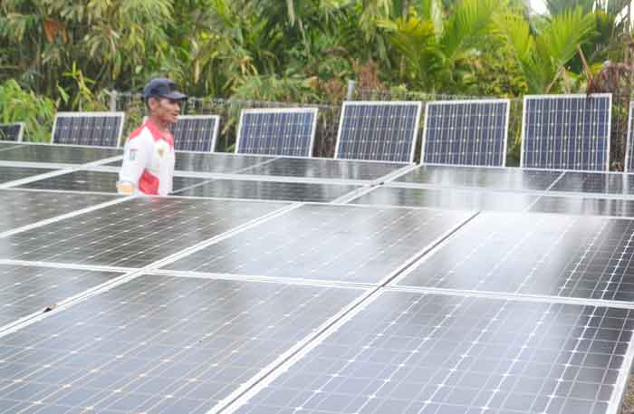Seorang warga Desa Gajah Bertalut Kecamatan Kampar Kiri Hulu, Kabupaten Kamar, sedang berada di antara panel solar Pembangkit Listrik Tenaga Surya (PLTS) di desanya.