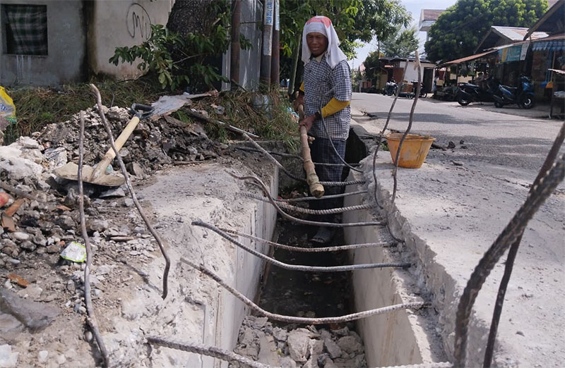 Pekerja terlihat membangun ulang jembatan drainase