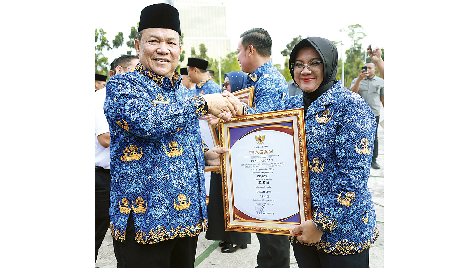 Plt Gubernur Riau SF Hariyanto menyerahkan penghargaan Universal Health Coverage kepada Bupati Siak Afni Z pada peringatan Hari Kesehatan Nasional (HKN) 2025 di halaman Kantor Gubernur Riau, Jalan Jenderal Sudirman, Pekanbaru, Senin (17/11/2025).