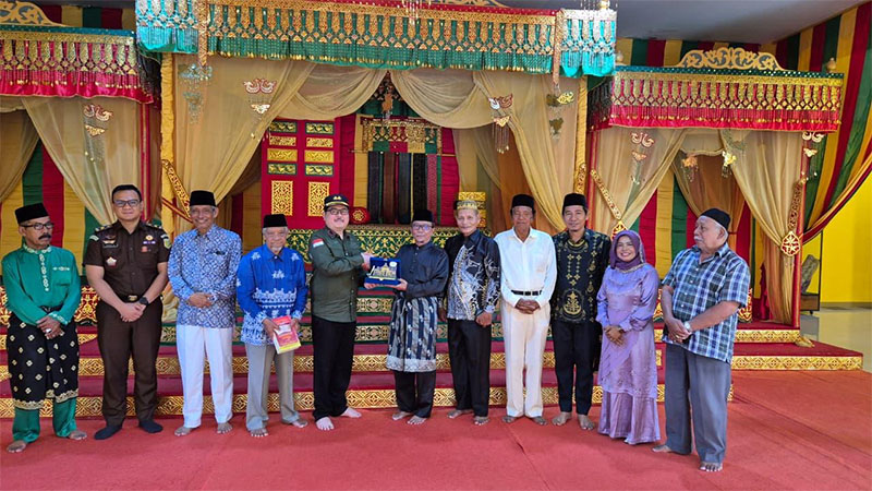 Kajari Siak Heri Yulianto bertukar cenderamata dengan Ketua DPH LAMR, Datuk Seri H Arfan Usman dalam kunjungan ke Lembaga Adat Melayu Riau (LAMR) Kabupaten Siak, Kamis (20/11/2025).