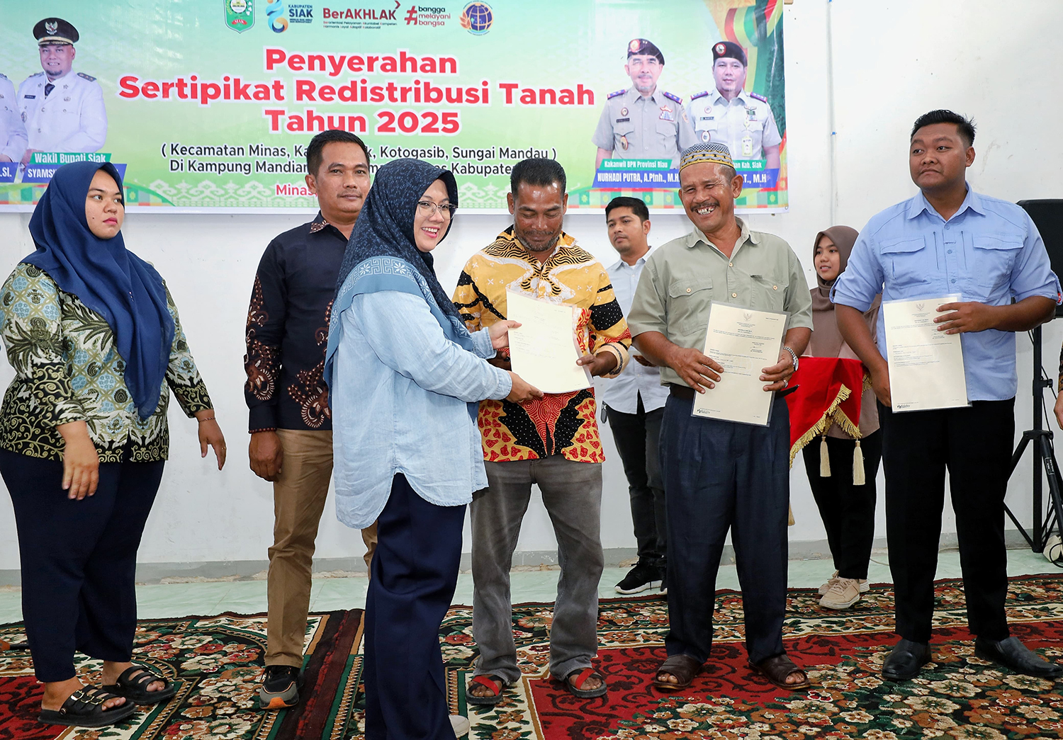 Bupati Siak Afni Z menyerahan sertifikat hak milik program TORA kepada warga Mandi Angin Minas, Kamis (20/11/2025).