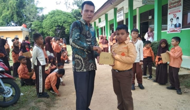 Kepala SDN 015 Desa Ketaping Jaya Kecamatan Inuman Yuasdar, bersama murid-murid beberapa hari lalu.