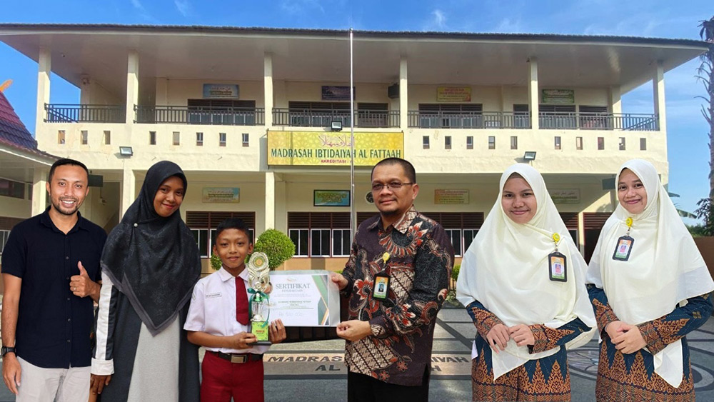 Kepala MI Al Fattaah H Roudhatul Firdaus Lc MPd menyerahkan sertifikat penghargaan peraih medali perunggu di OMI 2025 kepada Khilan Akala Arka