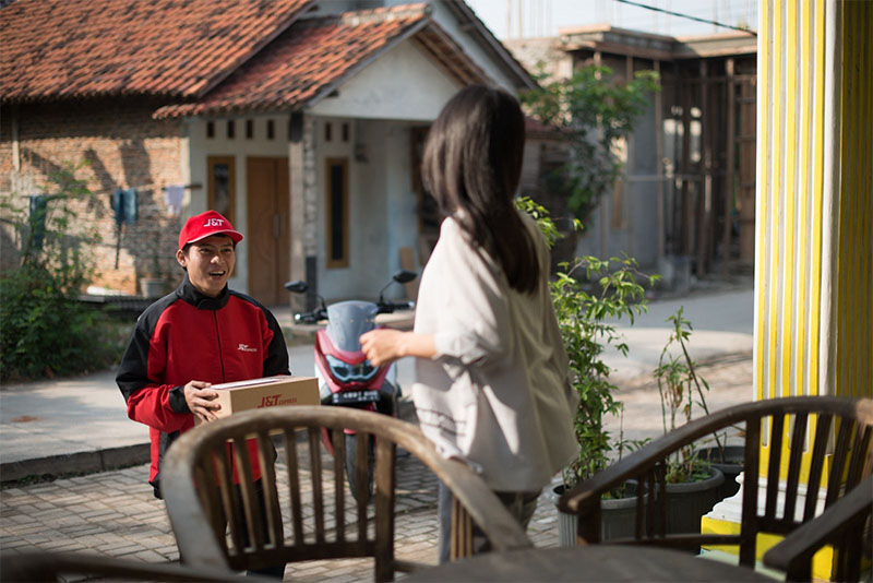 Kurir J&T mengantarkan paket ke costumer.
