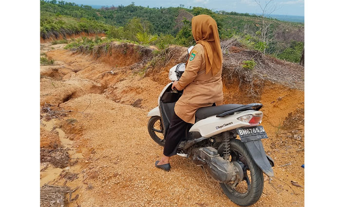 Guru Komite SDN 016 Rambah Masdalima pergi mengajar menggunakan kendaraan roda dua melewati jalan setepak yang terjal di kiri kanan jurang.