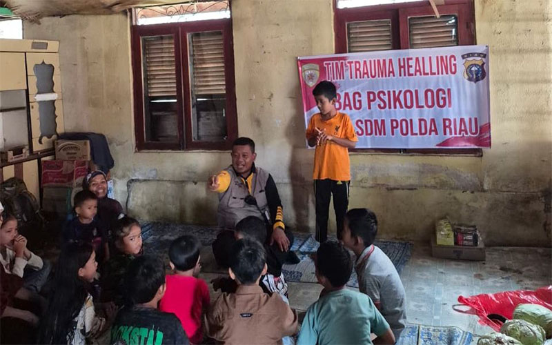 Tim trauma healing Polda Riau saat menghibur anak-anak korban banjir bandang di kamp pengungsian, Selasa (2/12/2025).
