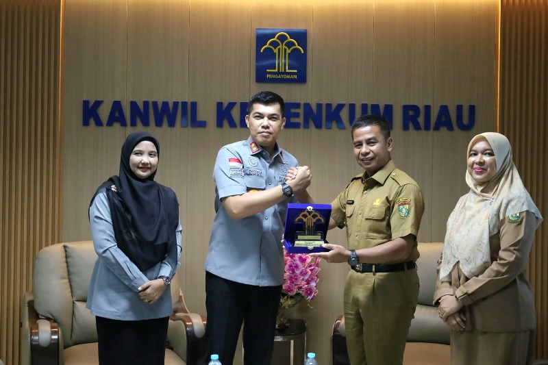 Kepala Kanwil Kemenkum Riau Rudy Hendra Pakpahan (dua kiri) menyerahkan plakat penghargaan Terbaik I Pos Bantuan Hukum bagi Kabupaten Kampar, yang diterima Bupati Ahmad Yuzar, Selasa (2/12/2025).