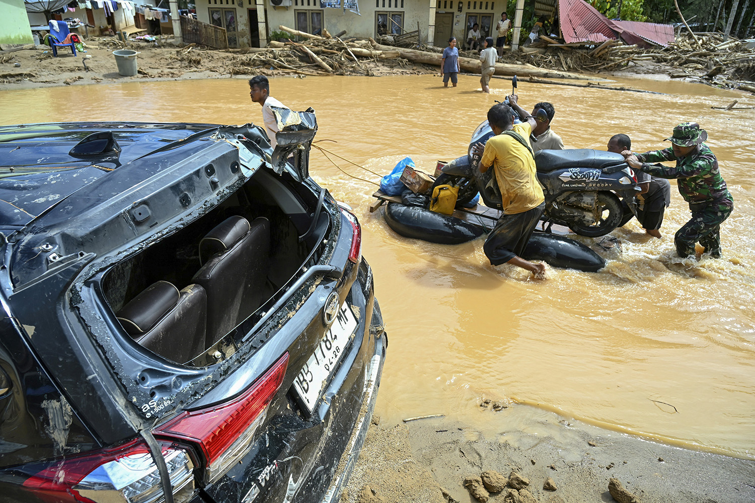 Warga mengevakuasi sepeda motor pakai rakit darurat di jalan yang tergenang akibat banjir bandang di Desa Tukka, Tapanuli Tengah, Sumatera Utara, Selasa (2/12/2025).