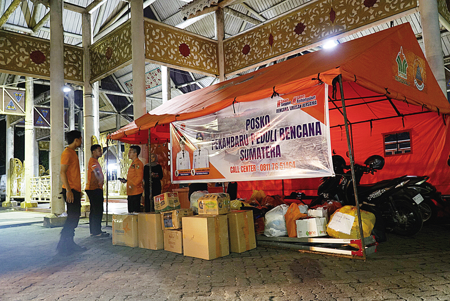 Petugas BPBD Kota Pekanbaru berjaga dan menerima bantuan sosial masyarakat di Posko Pekanbaru Peduli Bencana Sumatera yang berada di depan Purna MTQ, Jalan Jenderal Sudirman, Pekanbaru, Selasa (2/12/2025) malam.
