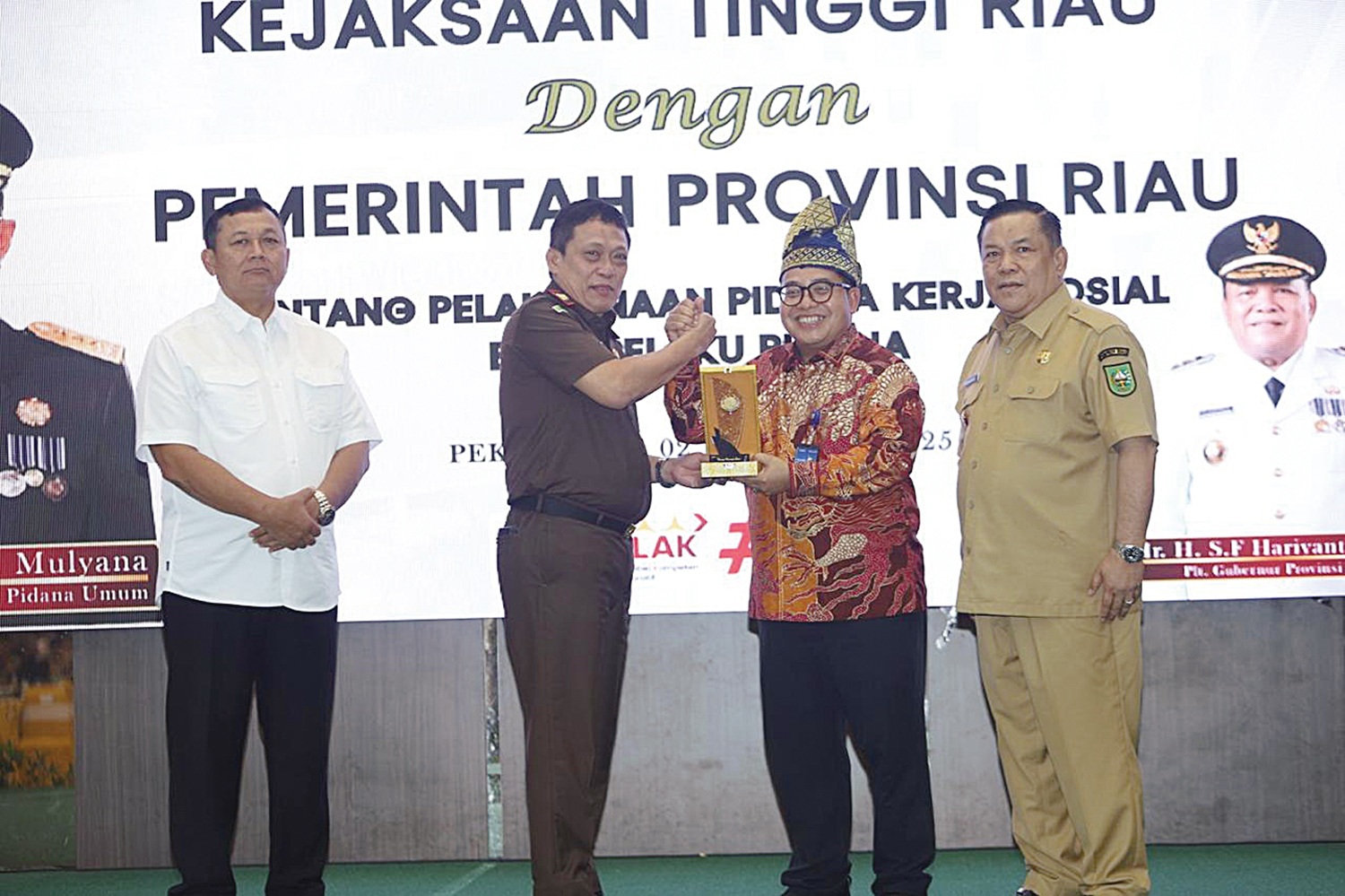 Plt Direktur Utama Jamkrindo Abdul Bari (bertanjak) menyerahkan plakat kepada Sesjampidum Kejagung Undang Mugopal didampingi Kajati Riau Sutikno dan Plt Gubernur Riau SF Hariyanto di sela-sela pengesahan kerja sama antara Kejati Riau dan Pemprov Riau pada