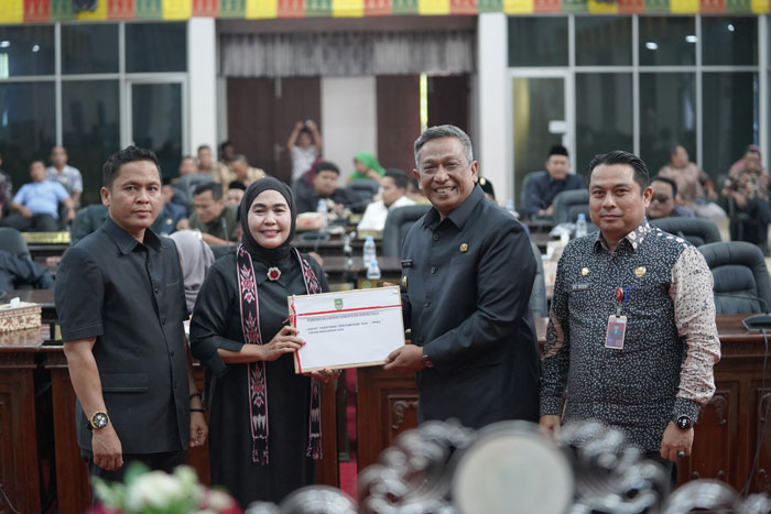 Bupati Rohul Anton ST MM menyerahkan dokumen rancangan KUA PPAS Tahun Anggaran 2026 kepada Ketua DPRD Rohul Hj Sumiartini dalam rapat paripurna di Gedung DPRD Rohul, Kamis (4/12/2025)