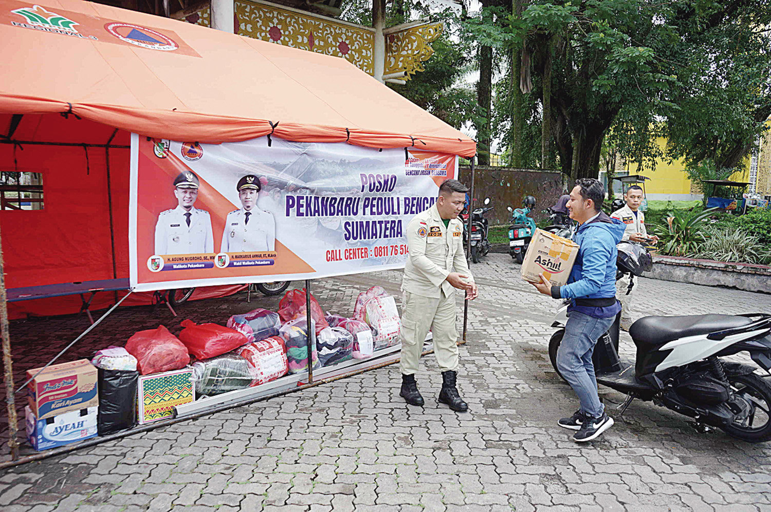 Petugas menerima bantuan yang diberikan warga untuk korban bencana alam Sumatera yang disalurkan melalui Posko Pekanbaru Peduli Bencana Sumatera di depan Purna MTQ Pekanbaru, Jalan Jenderal Sudirman, Kamis (4/12/2025).