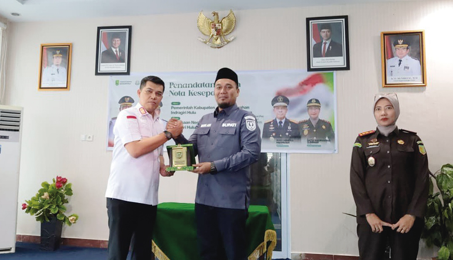 Disaksikan Kajari Inhu Ratih Andrawina Suminar (kanan), Kepala Kanwil Kemenkum Riau Rudy Hendra Pakpahan menyerahkan plakat penghargaan kepada Bupati Inhu Ade Agus Hartanto pada Kamis (4/12/2025).