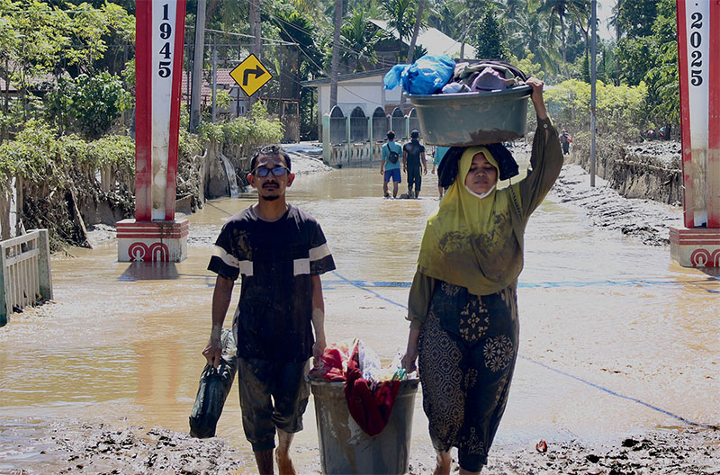 Warga membawa barang yang masih bisa diselamatkan dari rumahnya yang dihantam banjir bandang dan tanah longsor di Pidie Jaya