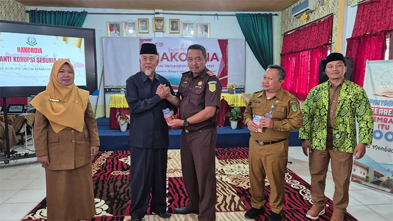 Kajari Inhil, Sugito SH memberikan stiker anti korupsi setelah memberikan materi dalam peringatan Harkordia 2025 di SMPN 1 Tembilahan, Selasa (9/12/2025).
