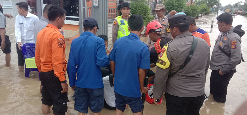 Personel BPBD Inhil dan pihak kepolisian mengevakuasi warga yang terperosok ke dalam parit saat air pasang dalam di Jalan Prof M Yamin Tembilahan, Selasa (9/12/2025).
