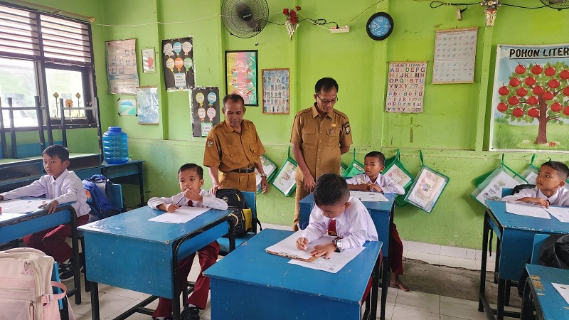 Plt Kadisdikpora Helmi (kanan) meninjau pelaksanaan ujian semester di UPT SDN 007 Pulau Lawas, Kecamatan Bangkinang, Selasa (9/12/2025).