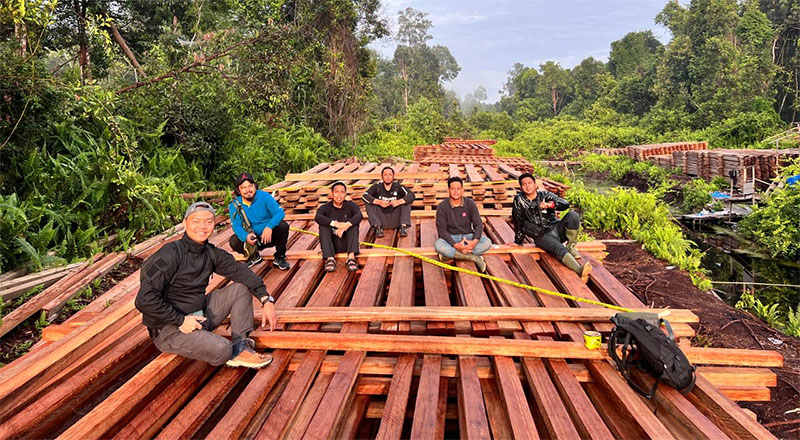Kasat Reskrim, AKP Arthur Joshua Toreh (kiri) foto bersama personel di atas tumpukan kayu olahan yang diduga hasil illegal logging, Rabu (10/12/2025).