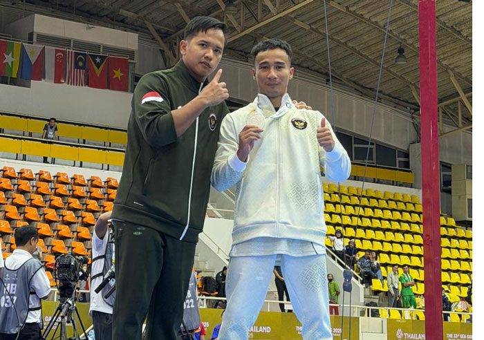 Pesenam Riau yang membela Indonesia di SEA Games M Aprizal (kanan) didampingi pelatih M Try Saputra memperlihatkan medali perak gelang-gelang SEA Games 2025 usai penyerahan medali di Bangkok