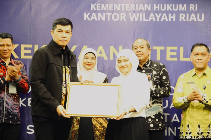 Kepala Kanwil Kemenkum Riau menyerahkan sertifikat mereka kepada pemiliknya disela-sela kegiatan Diseminasi Kekakayaan Intelektual yang digelar Kamis (11/12/2025).