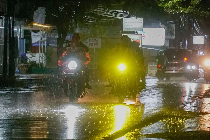 Pengendara sepeda motor menerobos guyuran hujan saat melintas di Jalan Cipta Karya, Pekanbaru.