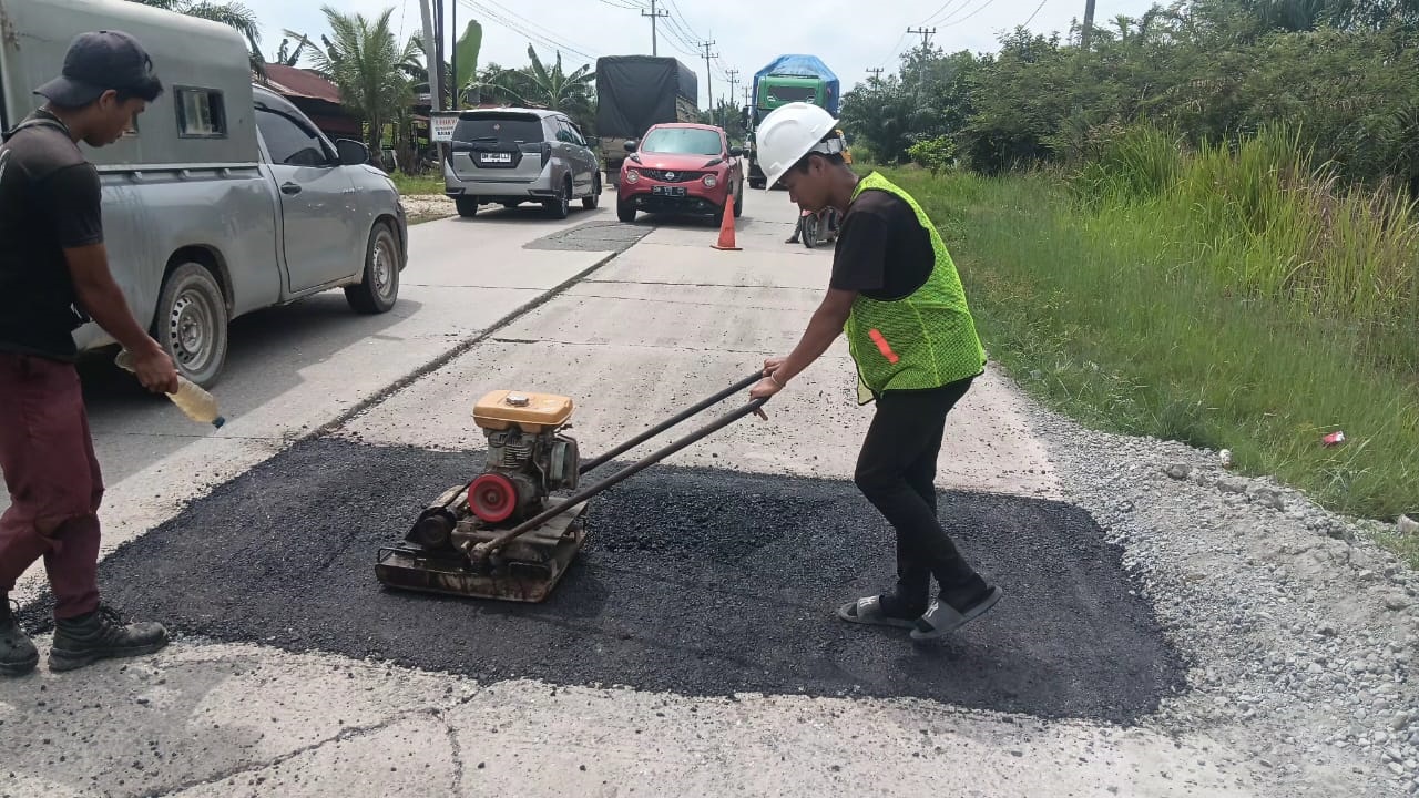 Petugas dari Badan Pengelolaan Jalan Nasional Wilayah Riau saat memperbaiki ruas jalan Lintas Timur di Kabupaten Pelalawan, Jumat (12/12/2025).